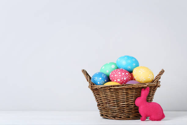 istock Colorful easter eggs in basket with fabric rabbit on grey background 993634548