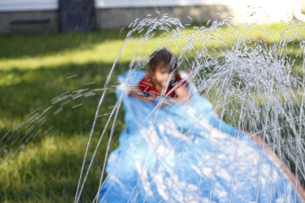 menina sorridente deslizar um deslizamento exterior e slide. foco seletivo na água na frente de criança - inflatable slide sliding child - fotografias e filmes do acervo