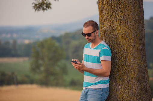 Modern man using cellphone in nature.