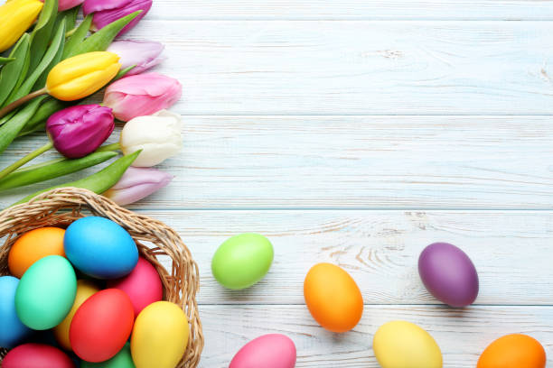 istock Colorful easter eggs in basket with tulips on wooden table 993636060