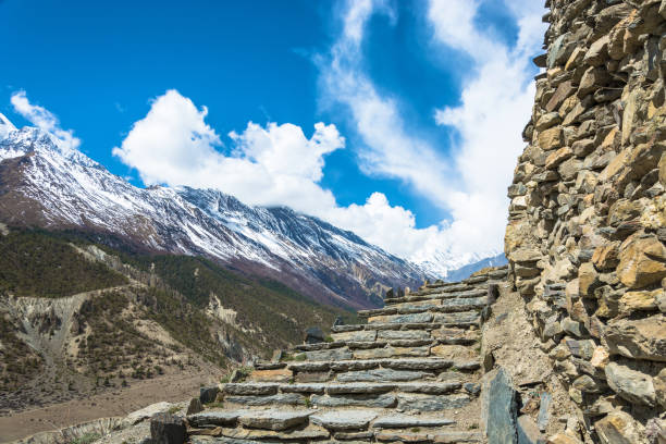 Stone stairs leading to the sky in the Himalayas, Nepal. Beautiful snowy mountain peaks and clouds.
