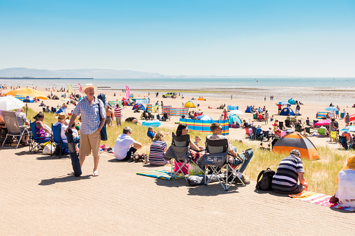 Swansea, United Kingdom -  June 30, 2018: People are enjoying a hot sunny summer day at the public beach in Swansea while waiting for the  free Welsh Air Show to start.