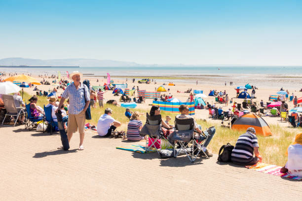 люди наслаждаясь жарким летним днем на пляже - wales beach editorial people стоковые фото и изображения