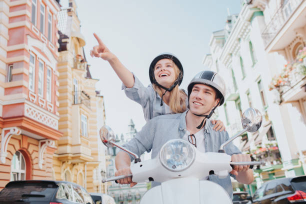 istock Excited girl is looking forward and pointing at the same direction. She and guy are wearing helmets. Guy is looking at the same direction. He is smiling 993657804