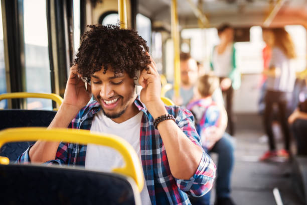 istock Young cheerful handsome man is adjusting his headset and enjoying the bus ride. 993661148