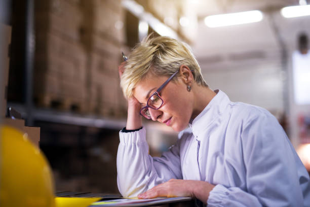 istock Young worried female worker is looking at the papers in the folder while holding her head. 993676656
