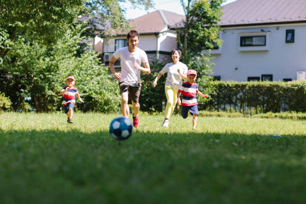 istock Family playing soccer in public park 993676700