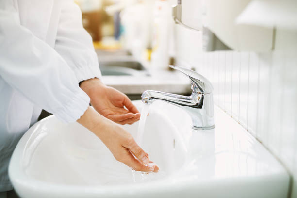 istock Female worker is washing hands before work in a bathroom sink. 993676882