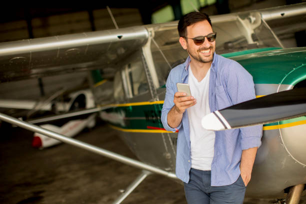 istock Young man using mobile phone in the airplane hangar 993680154