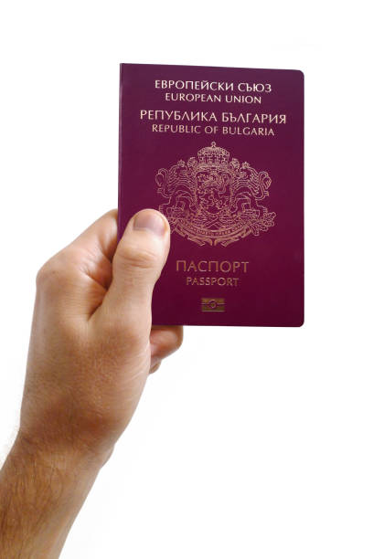 Close-up on a man's hand holding an Bulgarian passport against a white background.
