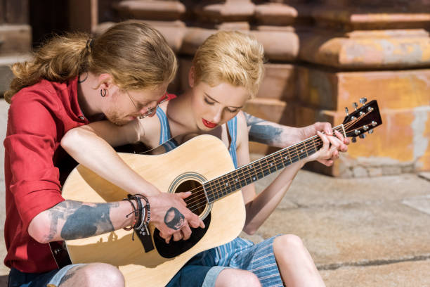young couple playing acoustic guitar together young couple playing acoustic guitar together acoustic guitar tattoos stock pictures, royalty-free photos & images