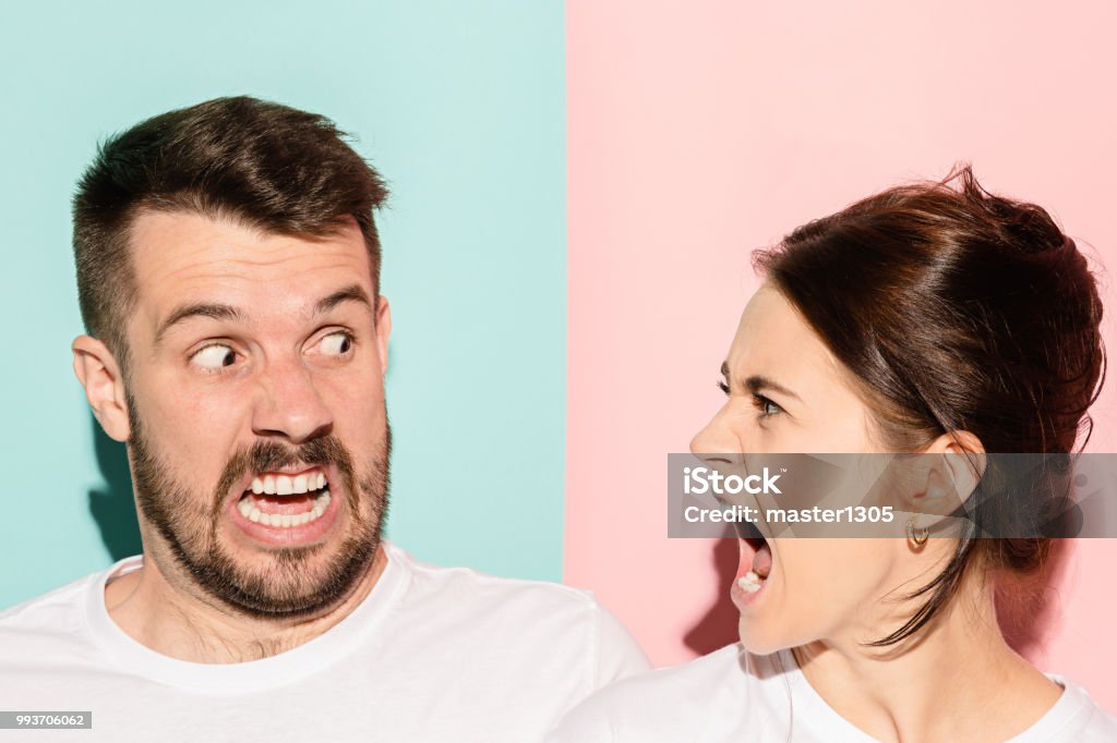 attractive angry couple fighting and shouting at each other The attractive angry couple fighting and shouting at each other. quarrel concept. The studio shot on trendy pink and blue background. Human emotions concept Couple - Relationship Stock Photo