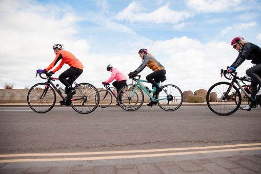 Group of female cyclists riding their bikes on a road.