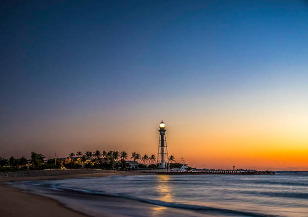 Hillsboro Inlet Lighthouse at Sunrise, Hillsboro Lighthouse with clouds at Sunrise looking over the Atlantic Ocean in Florida at the coastline with sand and surf