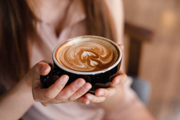 istock In selective focus of cappuccino cup in lady hands,blurry light design background 993718882