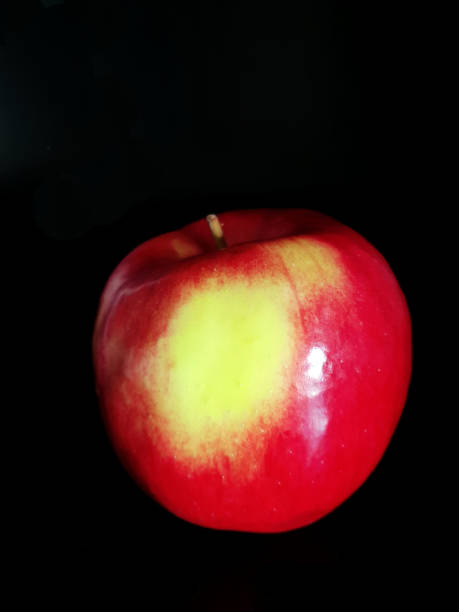 istock Red apple with twig and leaves on a black background 993723418