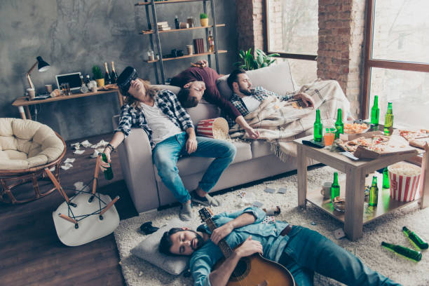 c’était la grande fête ! barbu, épuisés, fatigués, ivres les gars dorment après que les événements de la nuit à l’étage et canapé dans différente pose dans la salle de séjour, avoir un tas de détritus, ordures, détritus autour d’eux - bachelor home photos et images de collection