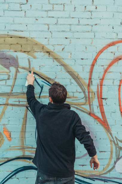 istock back view of man painting colorful graffiti on wall 993734158