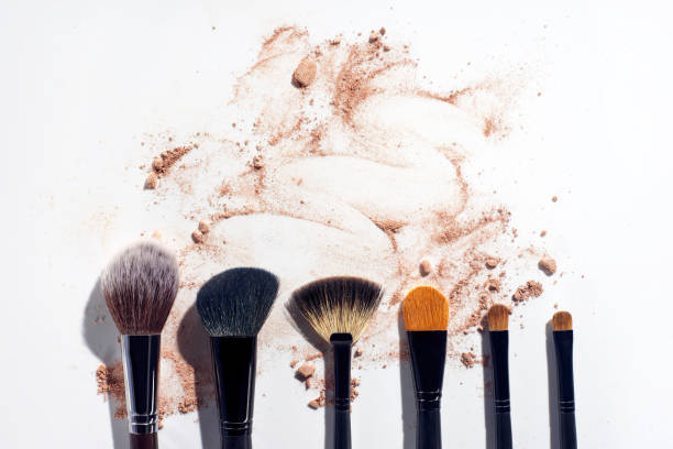istock Set of brushes in a row on white background with scattered face powder 993741722