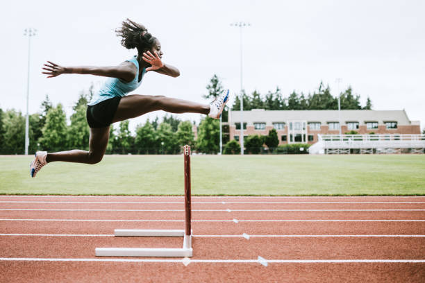 athlète féminine s’exécute des haies pour l’athlétisme - hurdle competition hurdling vitality photos et images de collection