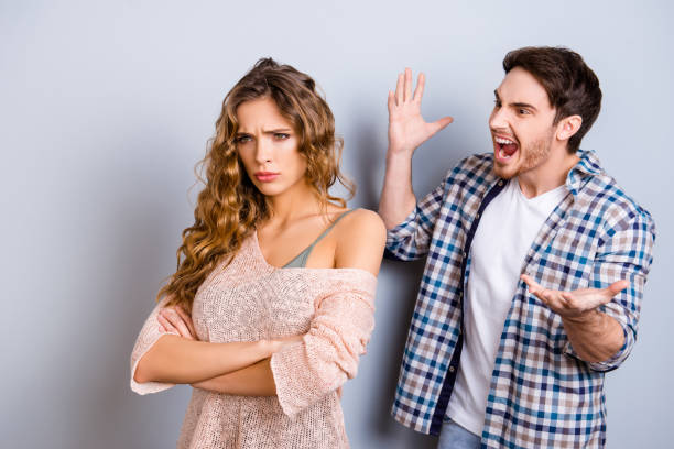 portrait of aggressive violent man gesturing with hands yelling loudly at crying lover with crossed arms isolated on grey background - beautiful female displeased furious imagens e fotografias de stock