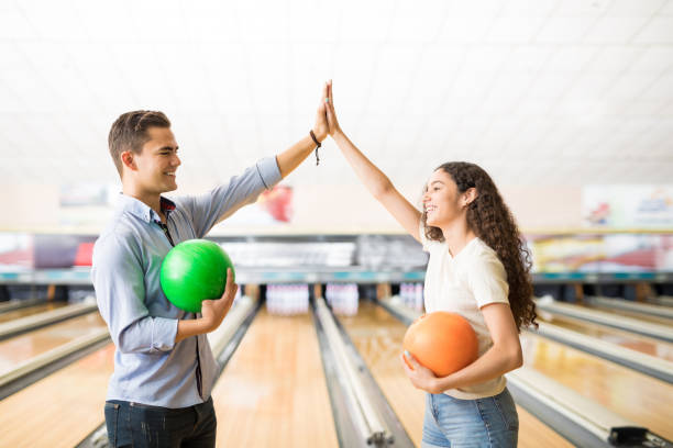 ボーリング場でハイタッチと teamspirit を表示お友達 - bowling holding bowling ball hobbies ストックフォトと画像