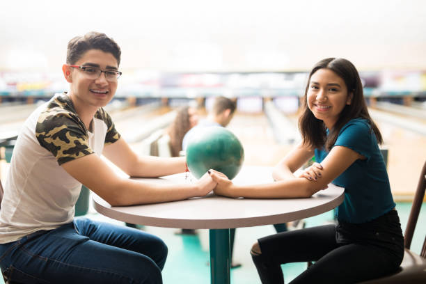 pareja adolescente con bola con las manos sobre la mesa - bowling holding bowling ball hobbies fotografías e imágenes de stock