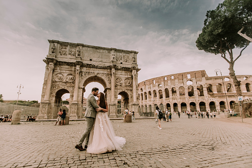 Young wedding couple by Arch of Constantine in Rome, Italy