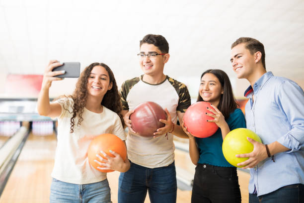 adolescentes capturar recuerdos de bolos en el teléfono móvil en el callejón - bowling holding bowling ball hobbies fotografías e imágenes de stock