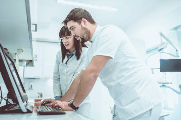 istock Male Dentist And Assistant Looking At Digital X-Ray Images On Computer 993767286