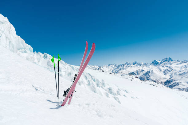 para nart i kijków narciarskich wystaje w śniegu na zboczu góry kaukazu na tle kaukaskiego pasma górskiego i błękitnego nieba w słoneczny dzień - sunny day mountain mountain range winter zdjęcia i obrazy z banku zdjęć