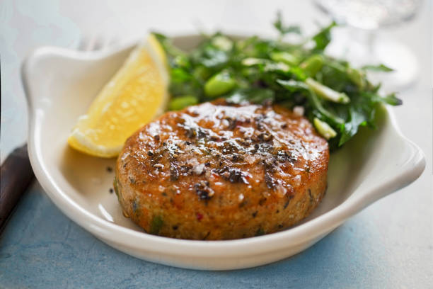 Thai style fish cakes with spicy soy glaze, green salad and lemon wedge stock photo
