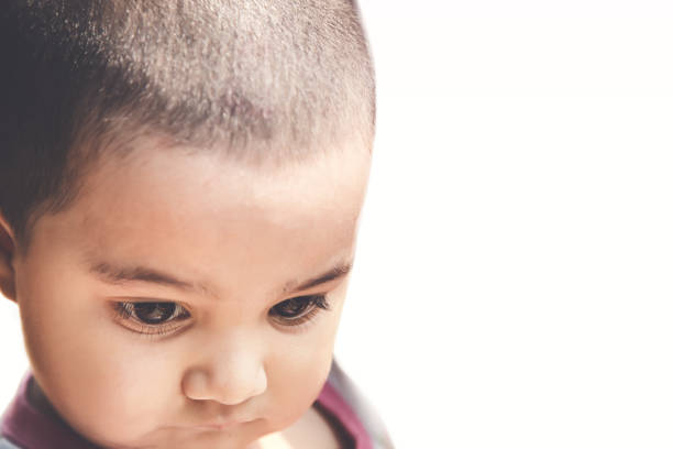 A 18 month old girl sitting down with a sad face