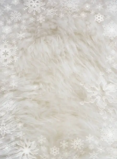 Fluffy white furry sheepskin and snowflakes christmas winter background