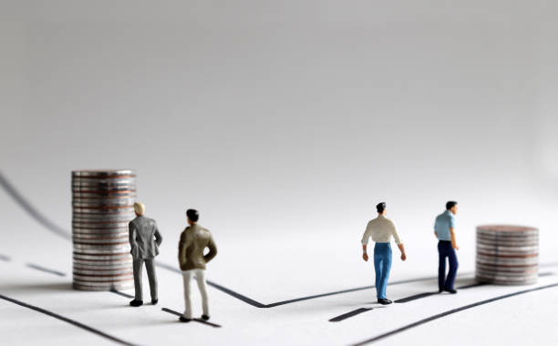 Economic income gap concept. Two pile of coins and miniature people on two paths. stock photo