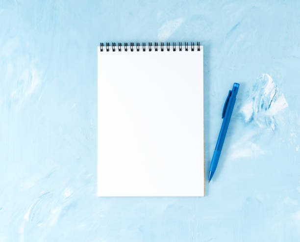 Top view of modern bright blue office desktop with pen or pencil, notepad. Mock up, empty space