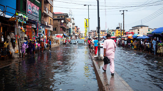 Lagos, Nigeria - November 24, 2017: Rainy season in African city - everyday traffic in flooded market streets.
