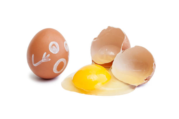 istock The egg on which is painted a face and a broken raw egg. Shell, yolk, protein isolated on a white background 993960374