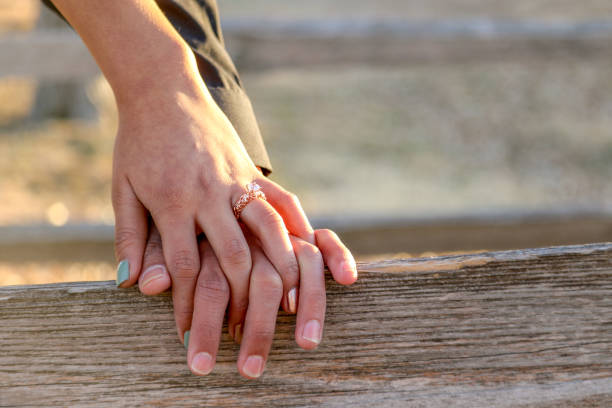 istock Newly Engaged Couple Holding Hands on Wood Plank 993962544