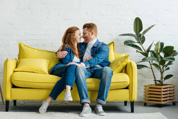 istock Redhead woman and man embracing on sofa 993964630