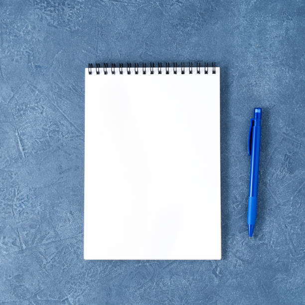 istock The open notepad with clean white page on aged dark blue stone table, top view 993965772
