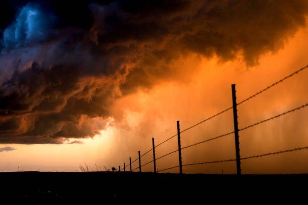 Pouring rain during a lightning storm framed by a low, orange sunset shot in the Great Plains Tornado Alley, Roswell, New Mexico.