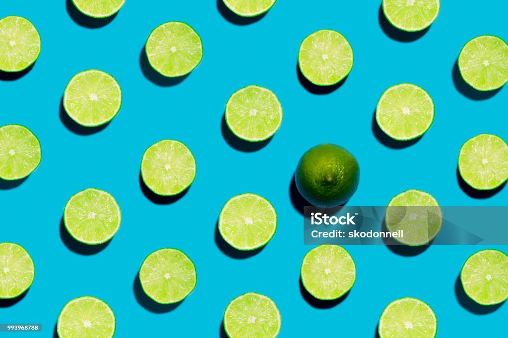 Lime geen aperto affettato su sfondo blu simmetrico con uno sbucciato aperto - Foto stock royalty-free di Cibo