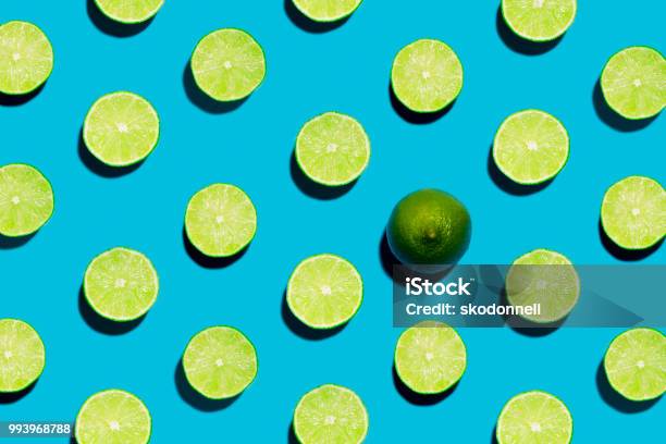 Sliced Open Geen Limes On Symmetrical Blue Background With One Peeled Open Stock Photo - Download Image Now