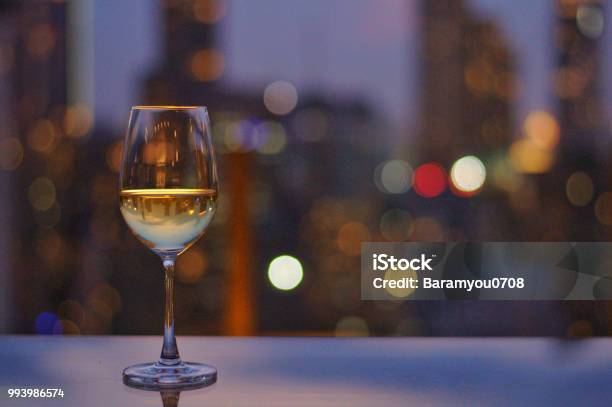 A Glass Of White Wine On Table Of Rooftop Bar With Colorful Bokeh Stock Photo - Download Image Now