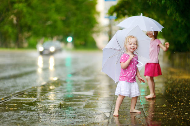 dos lindas hermanitas en un día lluvioso de verano - child dancing preschooler outdoors fotografías e imágenes de stock
