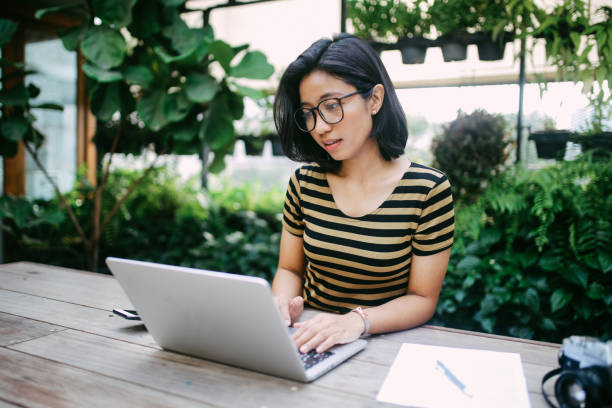 istock Smiling young Asian freelancer woman finishing up with work 994012084