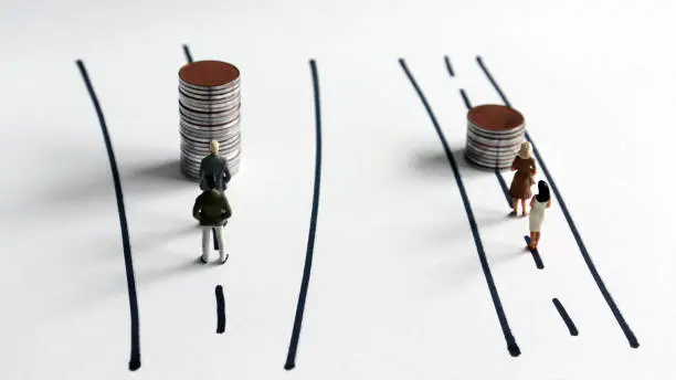 Concepts on the policy of gender discrimination in employment and wages. Miniature people and pile of coins.