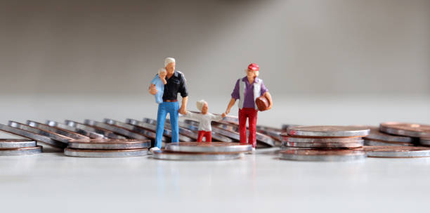 A family of four miniature people walking on coins. The concept of parenting and living expenses. stock photo