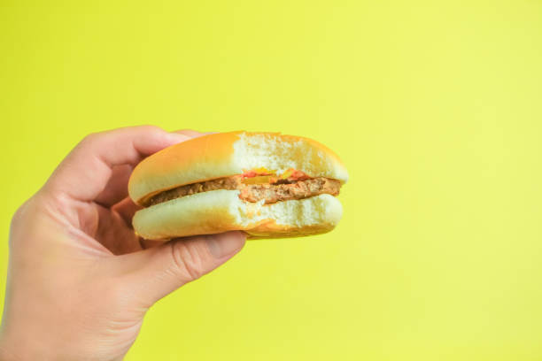 istock Images eating Hamburger with coffee.  yellow background. 994042154